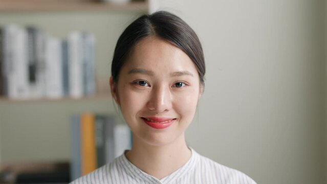 Close up portrait of young Asian woman look at camera and smile at office.