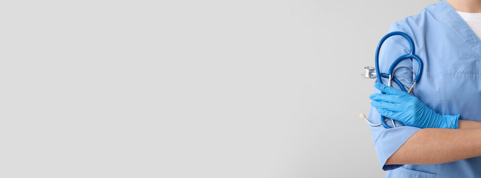 Female doctor holding stethoscope on light background with space for text