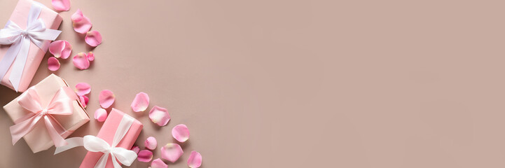 Gifts and pink rose petals on light color background with space for text