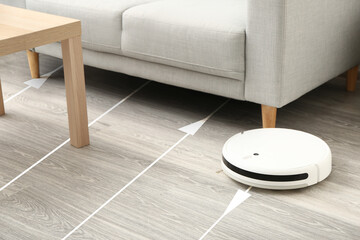 Modern robot vacuum cleaner on wooden floor in room