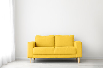 Comfortable yellow sofa near light wall