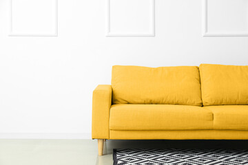 Comfortable yellow sofa near white wall
