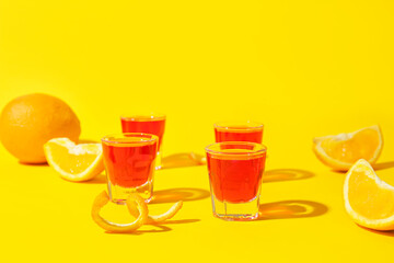 Shot cocktails and oranges on color background