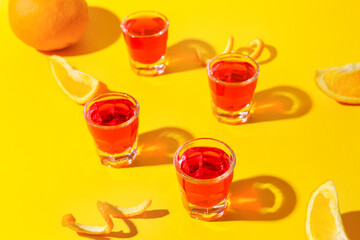 Shot cocktails and oranges on color background