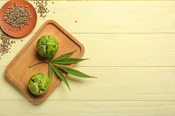 Board with tasty hemp muffins and seeds on color wooden background
