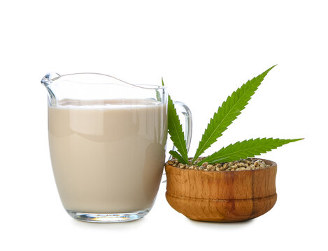 Jug of hemp milk and bowl with seeds isolated on white background