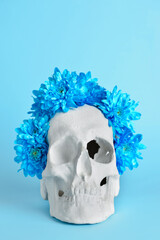 Human skull with flowers on blue background