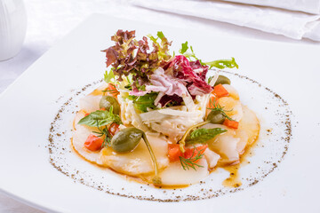 Salad with crab and scallop on a white plate