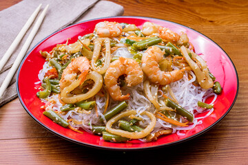 Rice noodles with shrimp and vegetables on wooden table