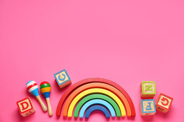 Wooden cubes with blocks and rattles on pink background