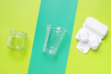 Glass plastic and cardboard on green background top view, waste sorting concept.