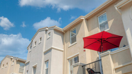 Panorama White puffy clouds Red umbrella on a balcony of a townhouse with cream wall exterio