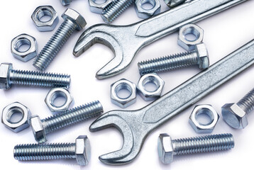Screws, nuts and wrenches on white background. Industrial background. Top view on various fasteners and spanners.
