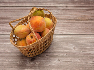 Group of fresh peaches fruits in a basket on a wooden table