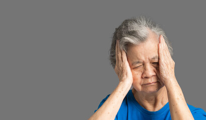 A senior woman who has a severe headache while standing on a blue background