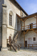 stone building with unusual windows and a wooden staircase to the second floor. outdoor wooden staircase in the castle