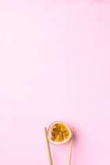 Obraz na płótnie Canvas Fresh passion fruit with chopsticks on pink background, Tropical fruit in summer season