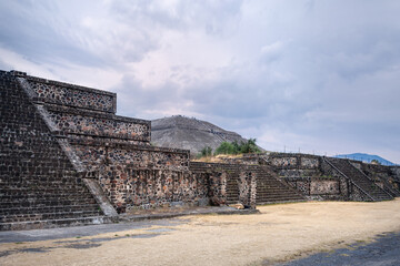 Teotihuacan archeological site in Central Mexico-Typical building flanking the Avenue of the Dead, main north-south artery in the ancient pre-Aztec City. People climbing the pyramid of the sun behind.