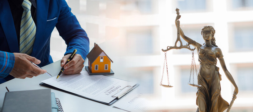 Real estate business concept, businessman signing a contract, house name and spinning image of the goddess of justice.