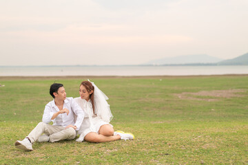 Naklejka na ściany i meble Happy young Asian couple in bride and groom clothing