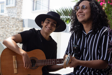 Fototapeta two smiling young Mexican male guitarist musicians enjoy playing their music outdoors on a sunny day. obraz