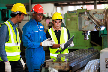 Training trainee concept. Yang male african american engineer explain the procedure for using the correct metal machine look at online  manual in laptop at factory.