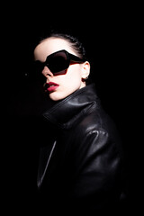 woman in leather coat and sunglasses, black background