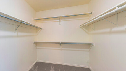 Panorama Empty walk in closet with gray carpet flooring and shelving unit