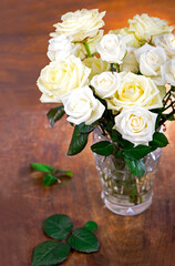 bouquet of blossoming roses in vase on a wooden background