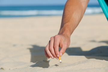 male hand stubbing cigarette into sand on the beach