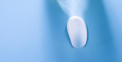 Fototapeta na wymiar smear of white cream on blue background with a beam of light 