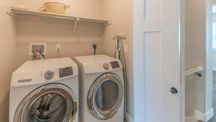 Panorama Reached in laundry with white bi-fold doors and laundry units below the shelf