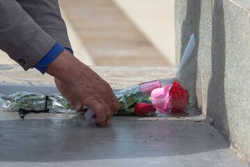 Laying flowers at the monument. An elderly man, a veteran with flowers at the monument.