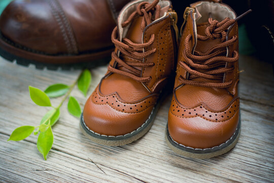 Still life with boots or brown shoes of daddy and son on on wooden table,fathers day