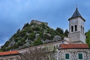 Catholic stone church with medieval fortress in background