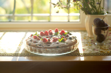 Tart with fresh raspberries and teapot, on wooden background