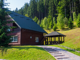 Cottage of winter ski resort Bukovel in Carpathian Mountains, Ukraine in Summer. Picturesque wooden house on the background of the Carpathians. Sights of the modern popular ski resort of Bukovel.