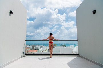 Happy woman beside a rooftop pool with a beautiful city and ocean view on background