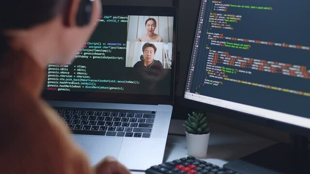 Asian woman developer programmer, software engineer, IT technical support center talking with team via video call. Working on computer overtime to check coding in bugging system.