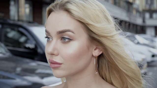 Portrait of a blonde with full lips and blue eyes on a background of parking