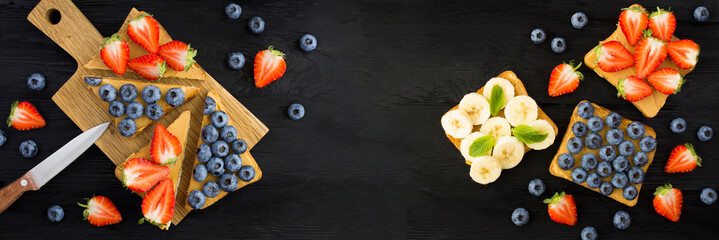 Banner. Sandwiches with peanut butter and fruit on the black wooden background. Top view. Copy...