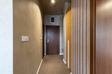 Interior of a carpeted hotel corridor doorway with brown wooden doors