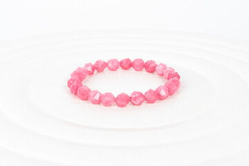 A beautiful bracelet of pink crystals on white leather table. Handmade jewelry. Natural stones.