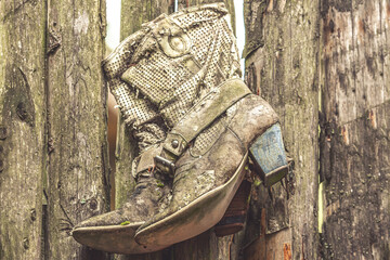 Close-up portrait of withered leather western boots on a wooden fence