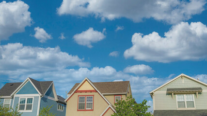 Panorama White puffy clouds Low angle view of three colorful houses with traditional designs