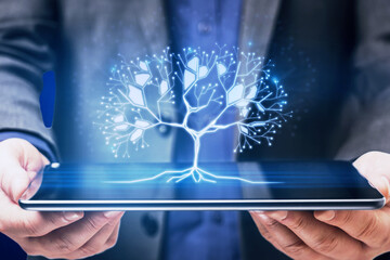 Close up of businessman hand holding tablet with glowing digital polygonal tree on blue background. Network, technology and database concept.