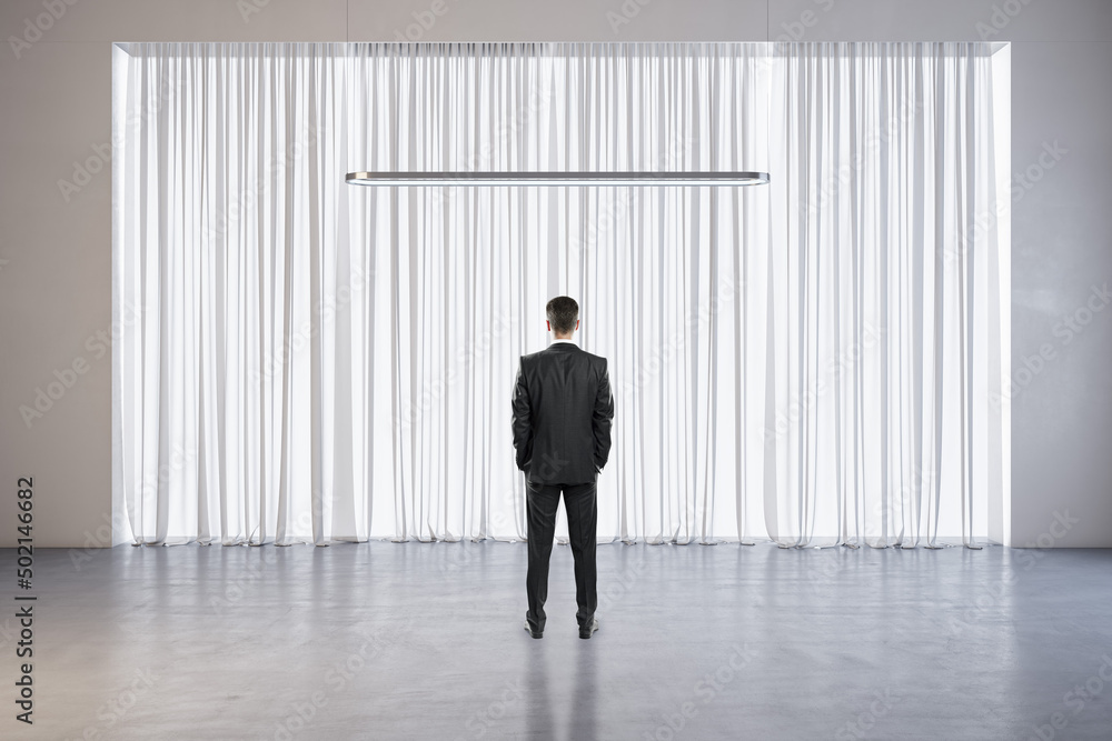 Poster back view of businessman standing in modern scene interior with curtains, lamp and mock up place.