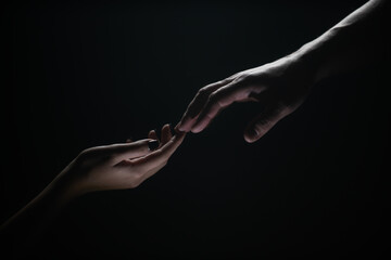 Hands gesturing on black background. Giving a helping hand. Support and help, salvation. Hands of two people at the time of rescue. Romantic touch with fingers, love. Hand creation of adam.