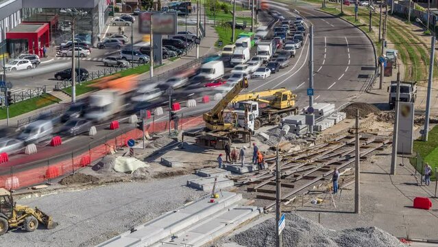 Loader crane for loading and unloading sleepers from truck which stands on a road construction site aerial timelapse