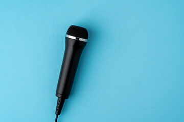 Black microphone in metallic tones, shallow depth of field on blue background, copy space top view